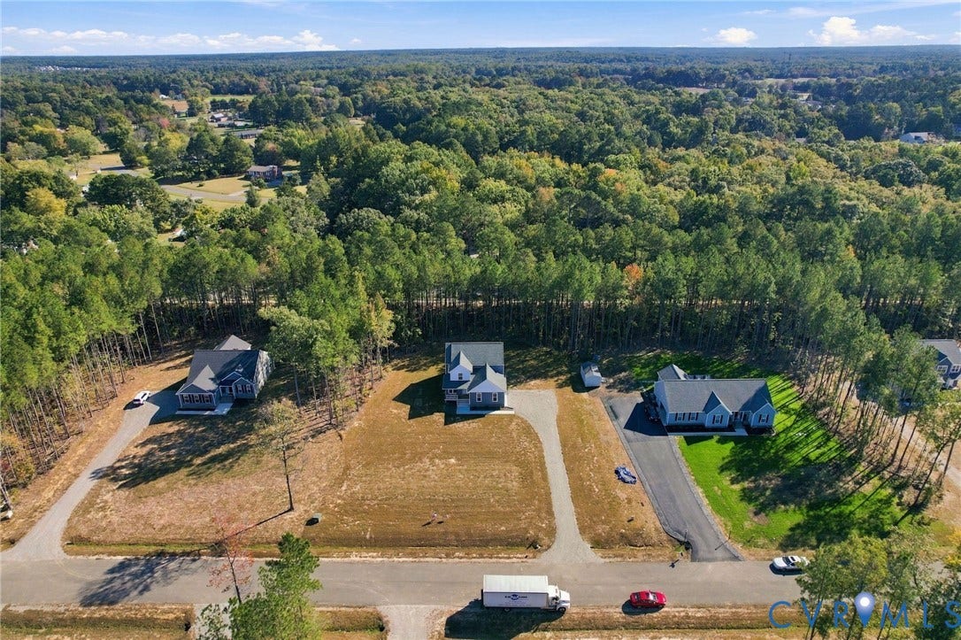 8209 Grantham Woods Way, Grantham Woods, Henrico, VA 23231 Aerial perspective of residential properties featuring asphalt driveways, open lot space, and extensive surrounding woodland canopy