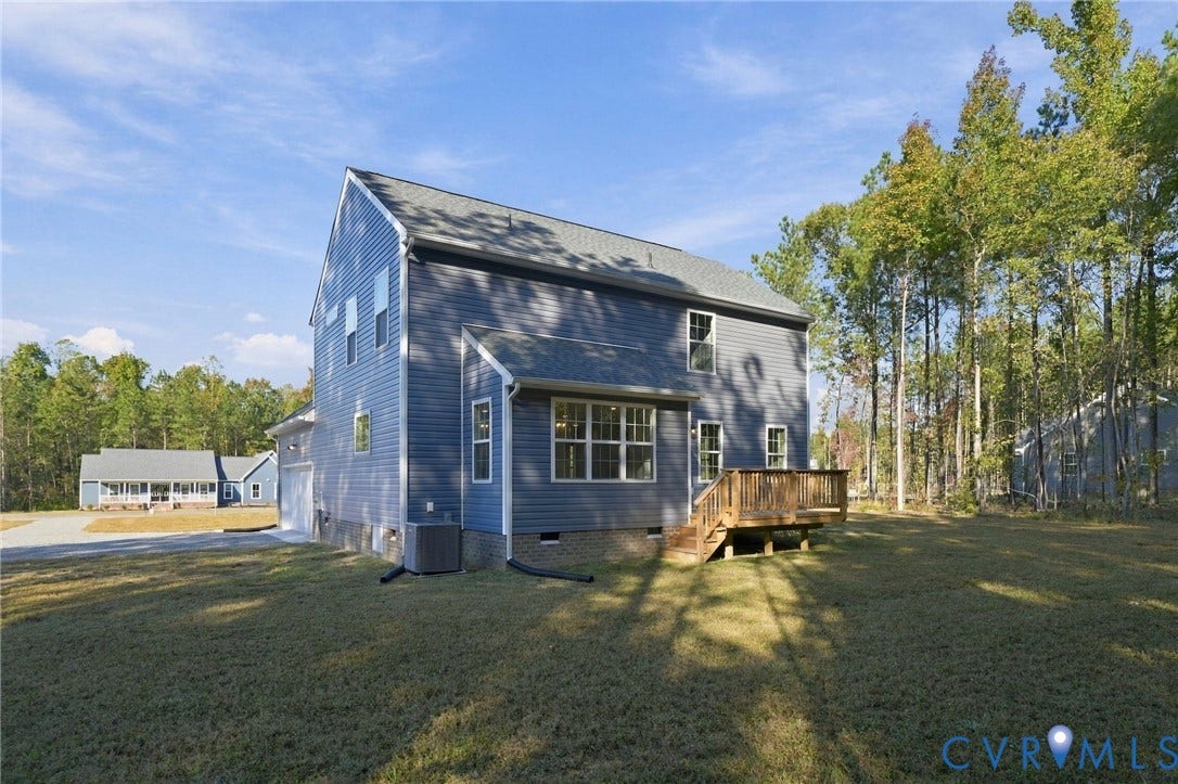 8209 Grantham Woods Way, Grantham Woods, Henrico, VA 23231 Two-story residence featuring blue horizontal siding, a gabled roof, an elevated wooden deck, and a grass-covered backyard surrounded by mature trees