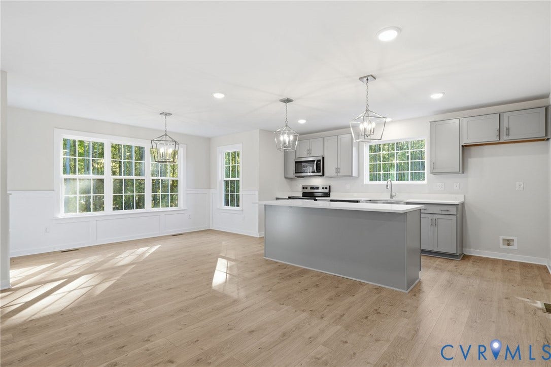 8209 Grantham Woods Way, Grantham Woods, Henrico, VA 23231 Kitchen featuring light grey shaker-style cabinetry, quartz countertops, a central island with integrated storage, wood-finish flooring, and multi-pane windows