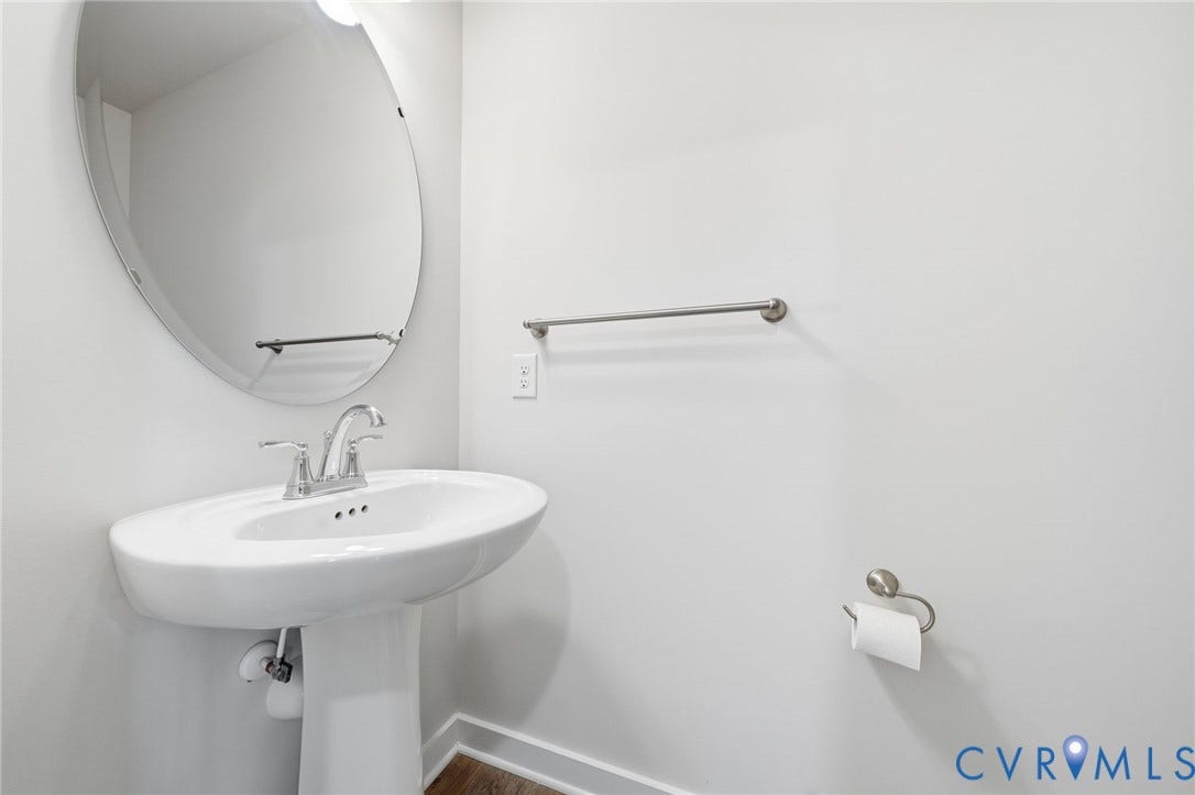 8209 Grantham Woods Way, Grantham Woods, Henrico, VA 23231 Oval wall-mounted mirror featuring a polished metal-finish faucet, pedestal sink, towel bar, and toilet paper holder