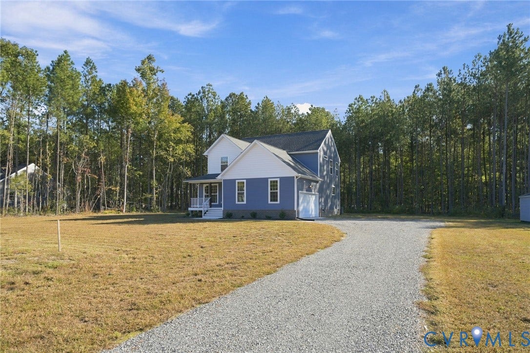 8209 Grantham Woods Way, Grantham Woods, Henrico, VA 23231 Two-story residence featuring blue siding with white trim, a covered front porch, attached garage, and a gravel driveway situated on a cleared lot