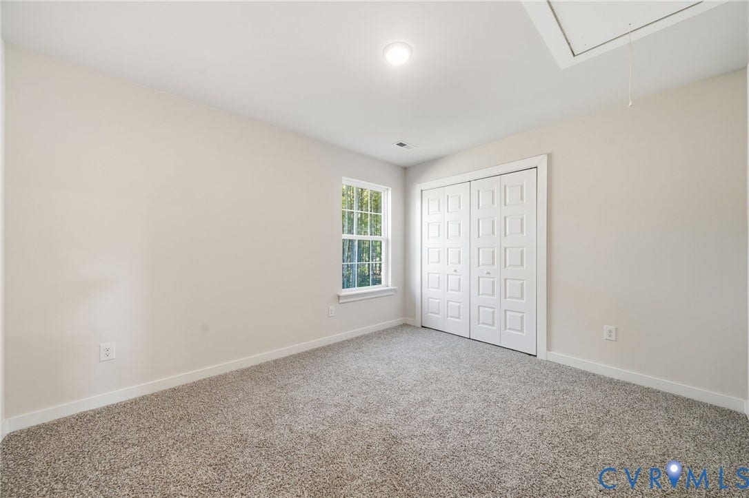 8209 Grantham Woods Way, Grantham Woods, Henrico, VA 23231 Neutral-toned interior space featuring neutral carpeting, a single-pane window, flush-mount lighting, and bi-fold closet doors with raised panels