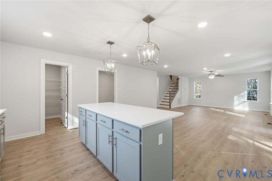 8209 Grantham Woods Way, Grantham Woods, Henrico, VA 23231 Kitchen island featuring light-toned cabinetry and a solid-surface countertop, wood-finish flooring, recessed lighting, geometric pendant fixtures, and a walk-in pantry with wire shelving