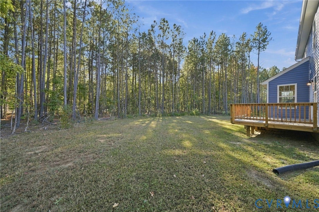 8209 Grantham Woods Way, Grantham Woods, Henrico, VA 23231 Rear yard featuring a wood deck, blue lap siding, and established pine trees
