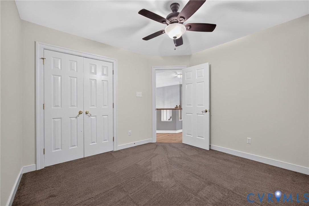 Neutral-toned walls, ceiling fan with integrated lighting, wall-to-wall carpeting, and double-panel doors
