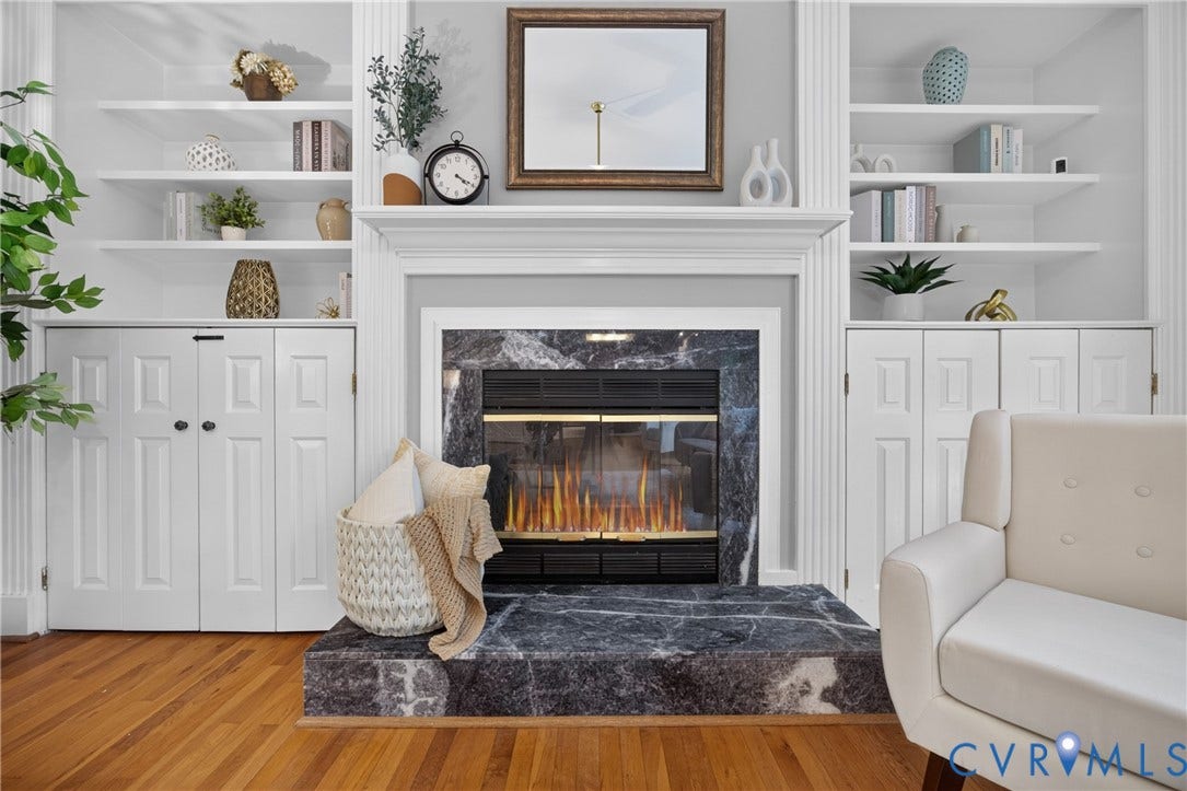 Fireplace featuring a stone surround and raised hearth, flanked by symmetrical built-in cabinetry with integrated shelving and base storage