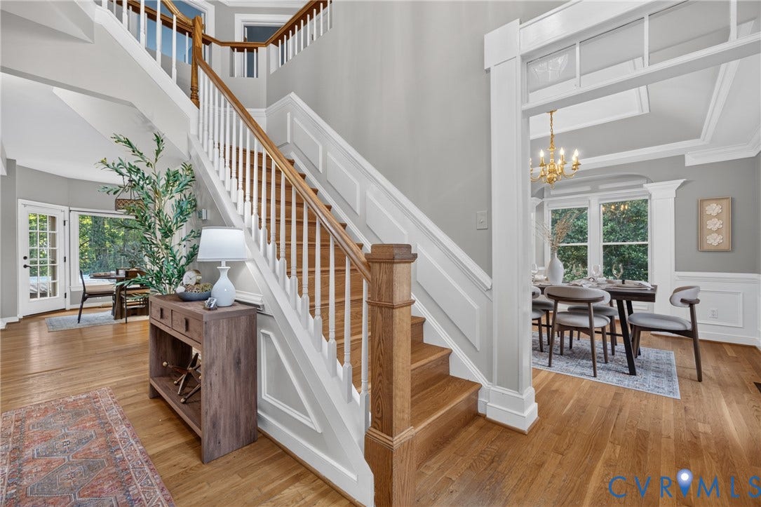 Foyer featuring a hardwood staircase with white balusters, wood-finish flooring, wainscoting, and crown molding
