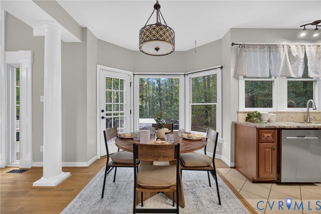 Breakfast area featuring a decorative pendant light, wood-finish flooring, a bay window, and a glass-paneled exterior door