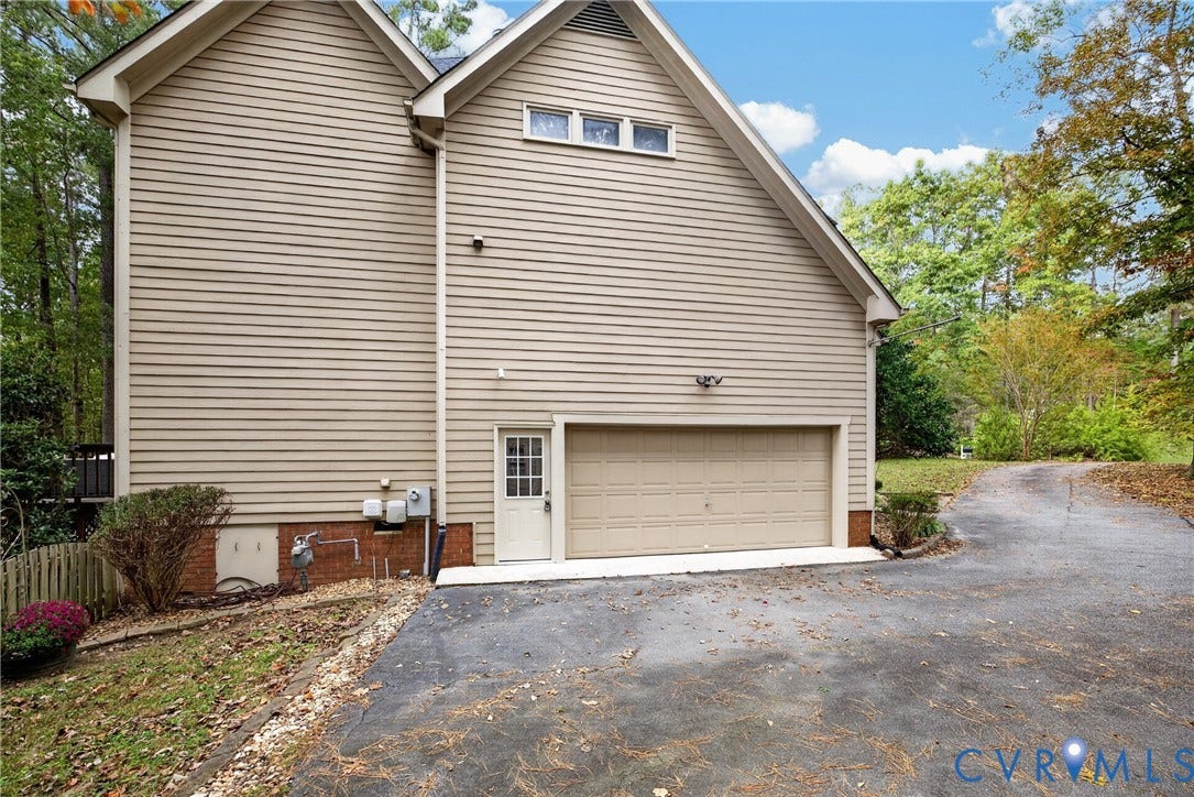 Exterior featuring horizontal siding, brick foundation, attached multi-car garage, and asphalt driveway