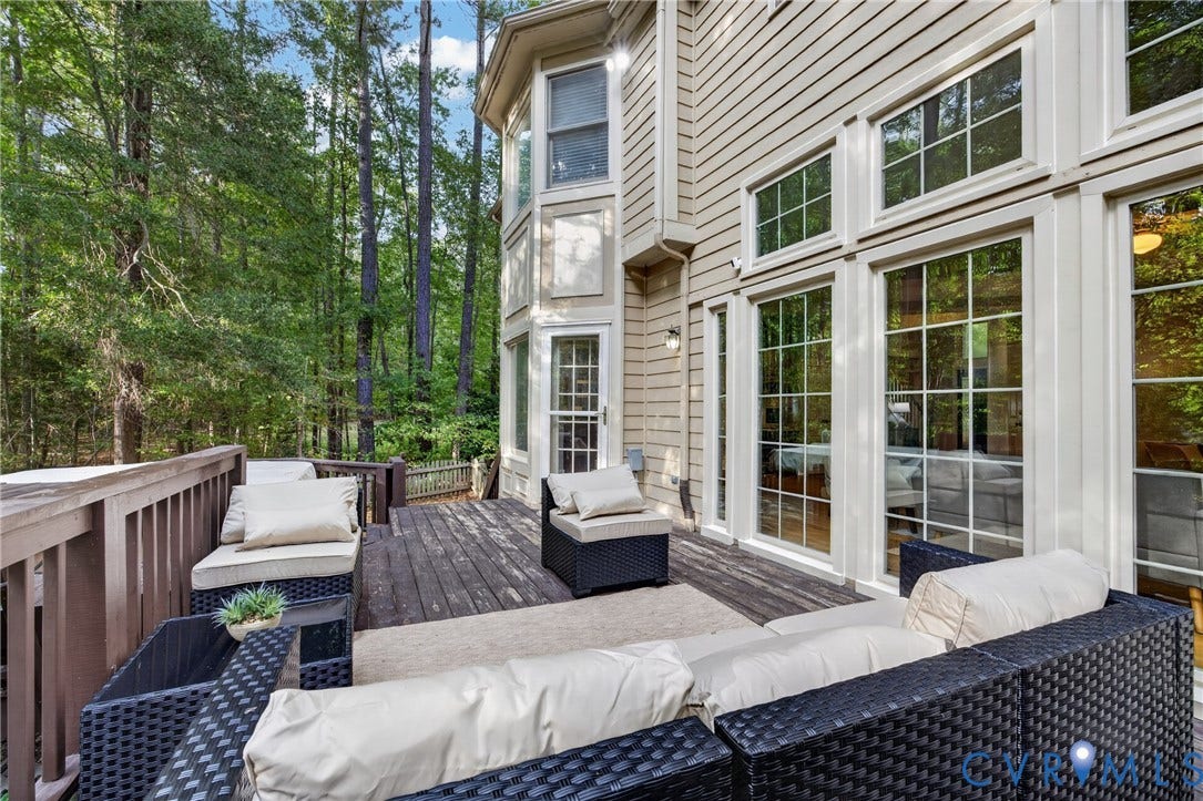 Expansive rear deck featuring wood-finish decking and integrated railing, complemented by multi-story window configurations and horizontal siding