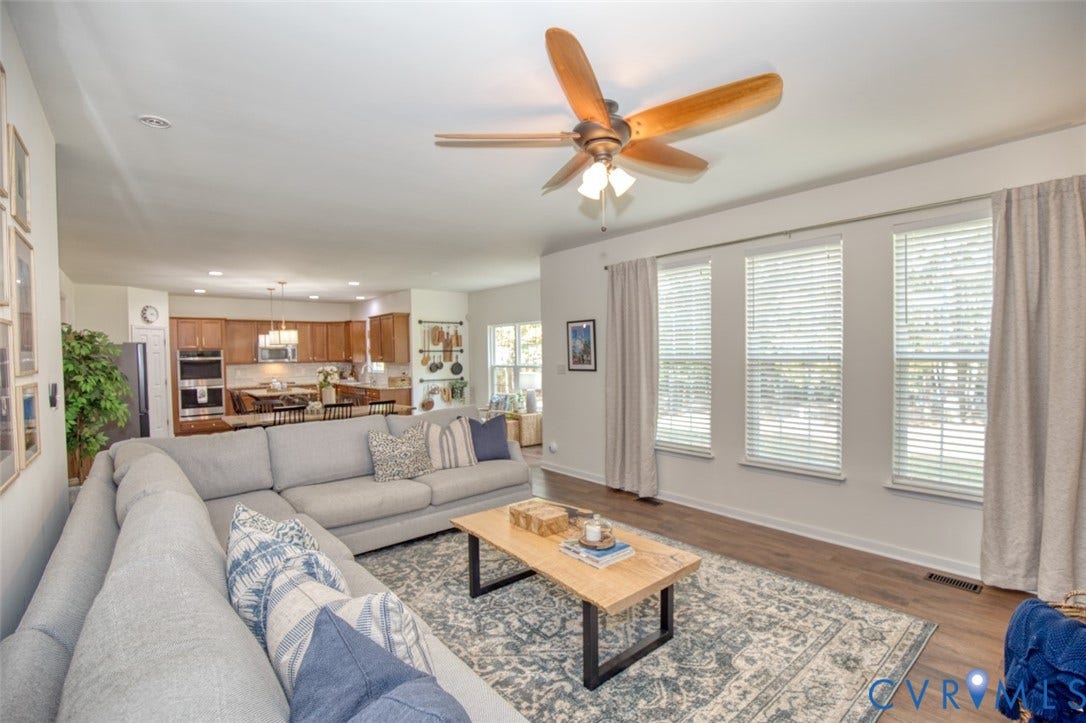 13501 Cooks Mill Court, Cooks Mill, Lanexa, VA 23089 Open-concept interior featuring wood-finish flooring, a multi-blade ceiling fan with integrated lighting, and a kitchen equipped with built-in stainless steel appliances and wood cabinetry