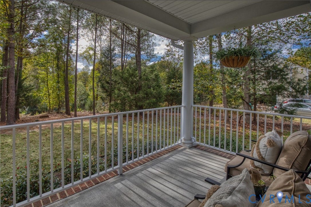 13501 Cooks Mill Court, Cooks Mill, Lanexa, VA 23089 Covered porch featuring concrete flooring, a classic column, and white metal railing, opening to a wooded landscape
