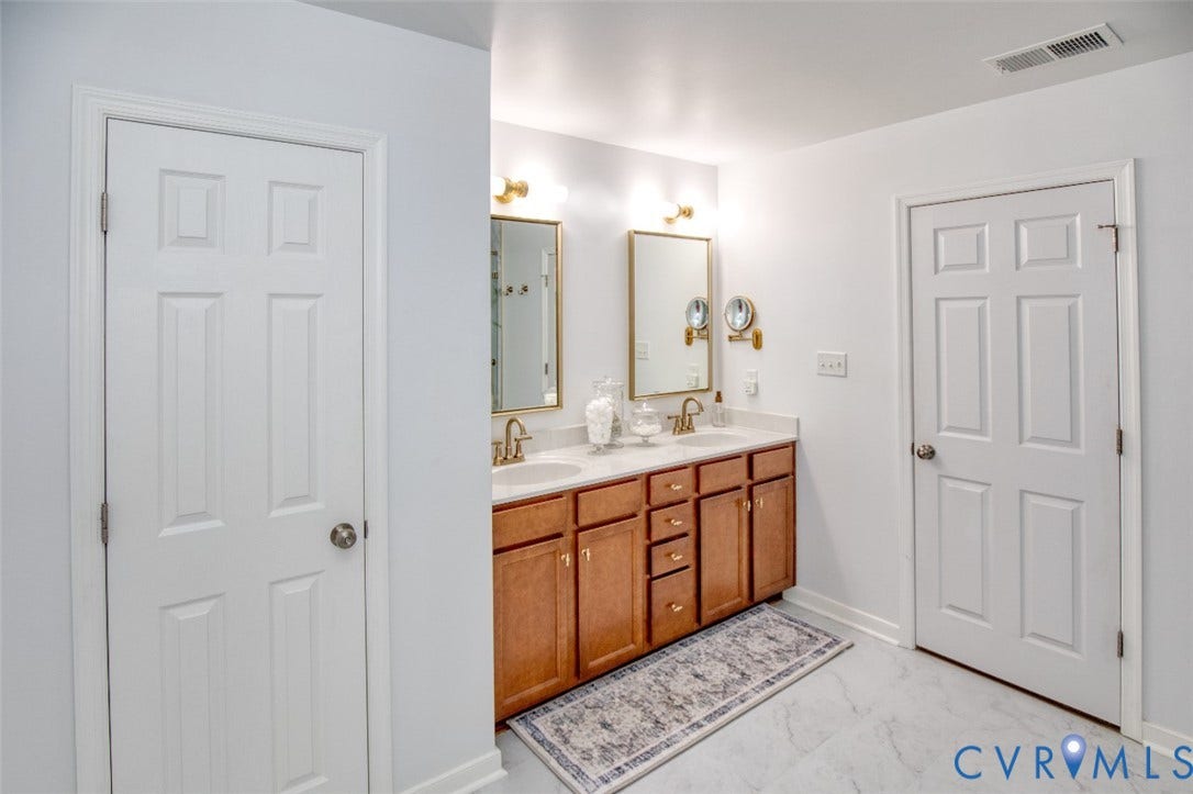 13501 Cooks Mill Court, Cooks Mill, Lanexa, VA 23089 Dual-sink vanity with wood-finish cabinetry, solid surface countertop, metallic faucets, and wall-mounted mirrors