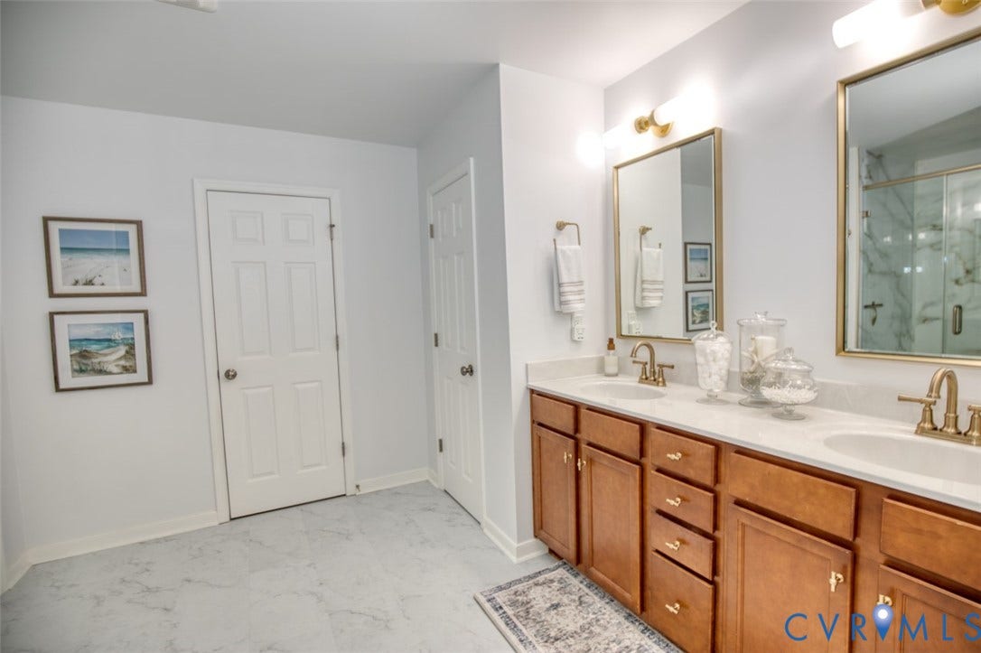 13501 Cooks Mill Court, Cooks Mill, Lanexa, VA 23089 Dual-sink vanity with light stone countertop, brass-finish faucets, wood cabinetry, and individual wall-mounted mirrors