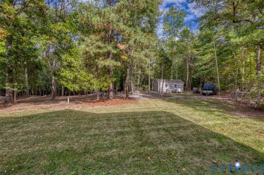 13501 Cooks Mill Court, Cooks Mill, Lanexa, VA 23089 Expansive backyard featuring a grass lawn, mature trees, and a detached storage structure