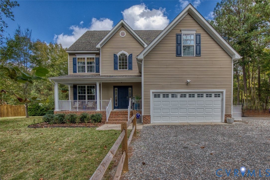 13501 Cooks Mill Court, Cooks Mill, Lanexa, VA 23089 Two-story residence featuring light-toned horizontal siding, a covered front porch with white railing, a two-car garage, and an arched transom window above the entrance