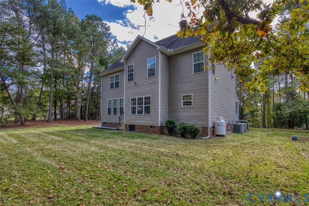 13501 Cooks Mill Court, Cooks Mill, Lanexa, VA 23089 Two-story residence featuring light-colored horizontal siding, brick foundation detailing, multi-pane windows, and an expansive rear yard bordered by mature trees