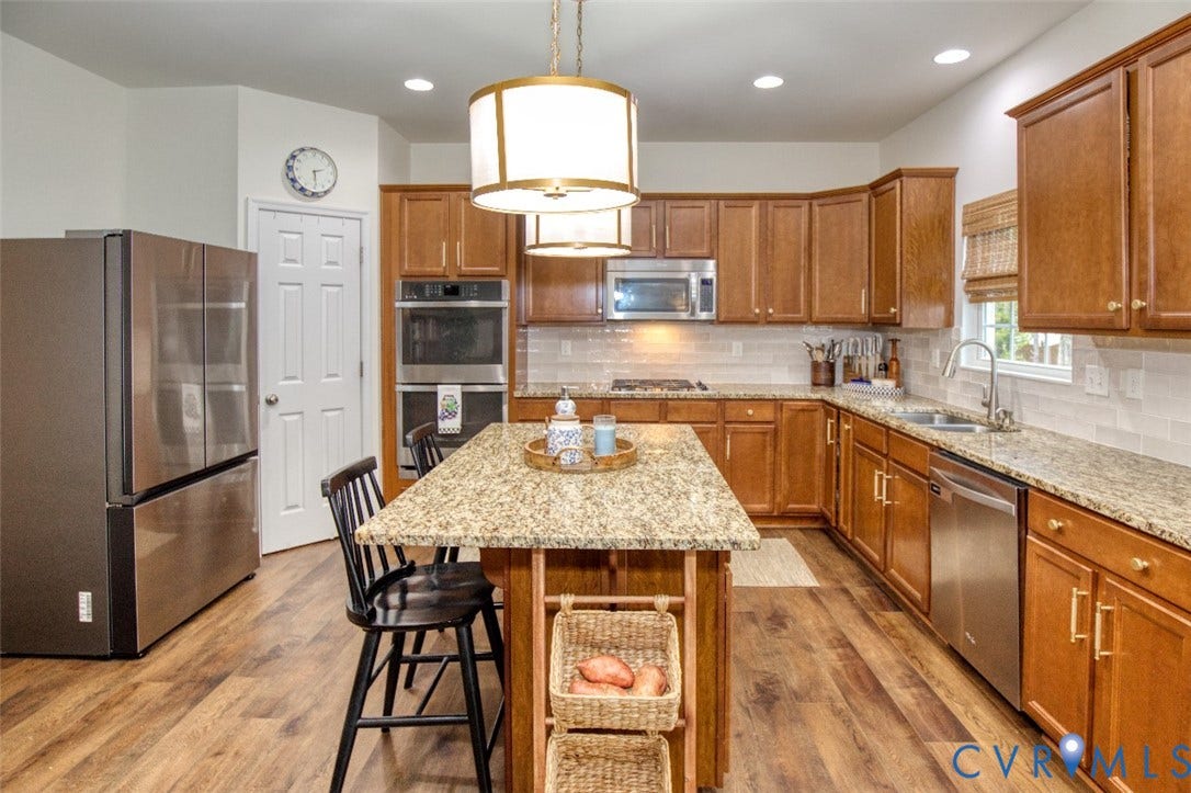 13501 Cooks Mill Court, Cooks Mill, Lanexa, VA 23089 Kitchen featuring wood cabinetry, stone-surface countertops, wood-finish flooring, a central island, and stainless steel appliances