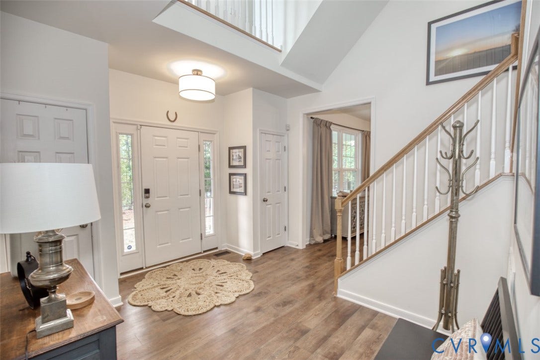 13501 Cooks Mill Court, Cooks Mill, Lanexa, VA 23089 Foyer featuring double-height ceilings, wood-finish flooring, a drum-style pendant light, and a staircase with a wooden handrail and white balusters