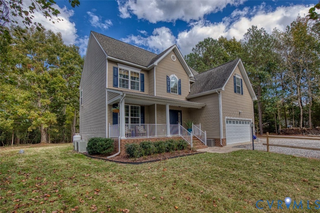 13501 Cooks Mill Court, Cooks Mill, Lanexa, VA 23089 Two-story residence featuring light-toned horizontal siding, brick foundation accents, a covered front porch with white railing, and an attached two-car garage