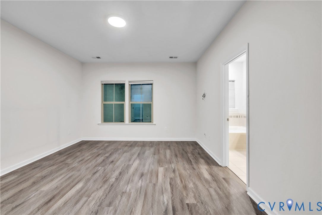 4511 Wistar Woods Trail, Richmond, VA 23228 Spacious room featuring wood-finish flooring, neutral wall tones, dual-pane windows, and a ceiling-mounted light fixture