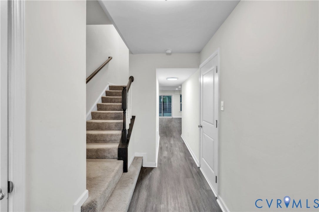 4511 Wistar Woods Trail, Richmond, VA 23228 Staircase featuring carpeted steps, a dark-stained wood handrail, and a white baluster, finished with wood-finish flooring and a white paneled door