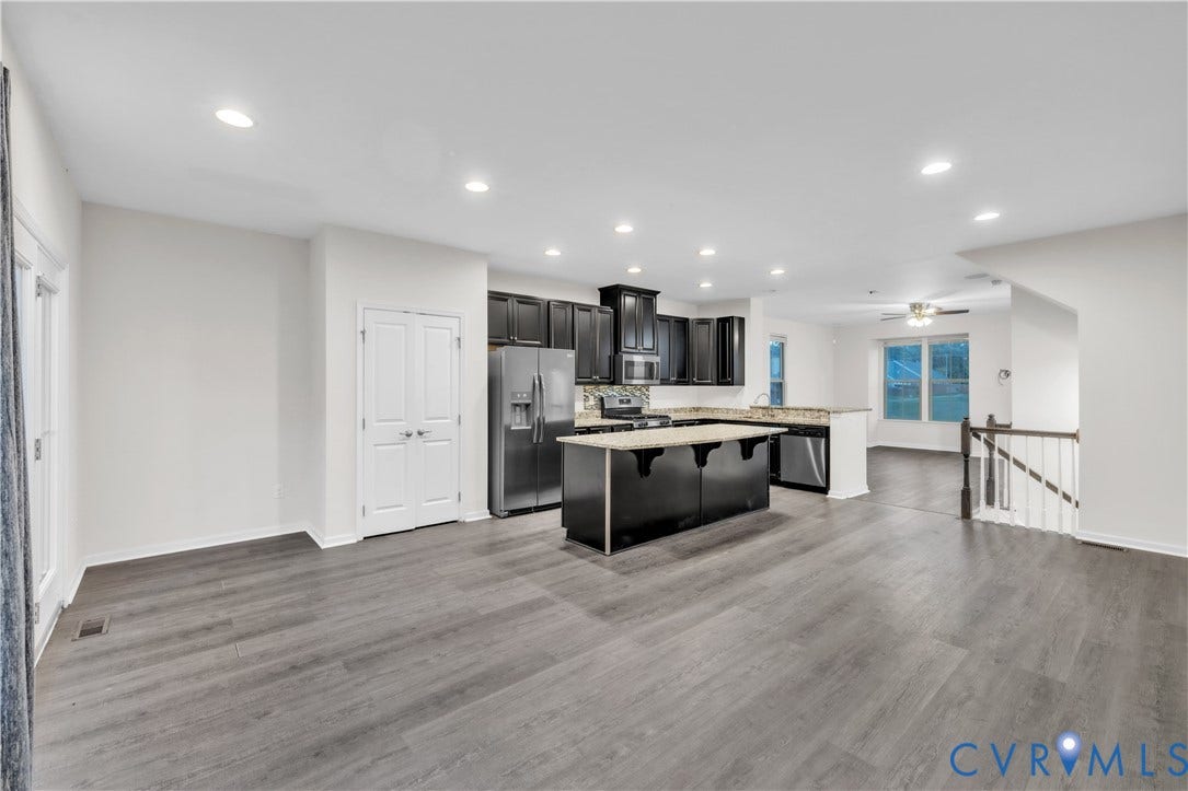 4511 Wistar Woods Trail, Richmond, VA 23228 Open-concept kitchen featuring dark cabinetry, a central island with a stone-finish countertop, stainless steel appliances, recessed lighting, and wood-finish flooring