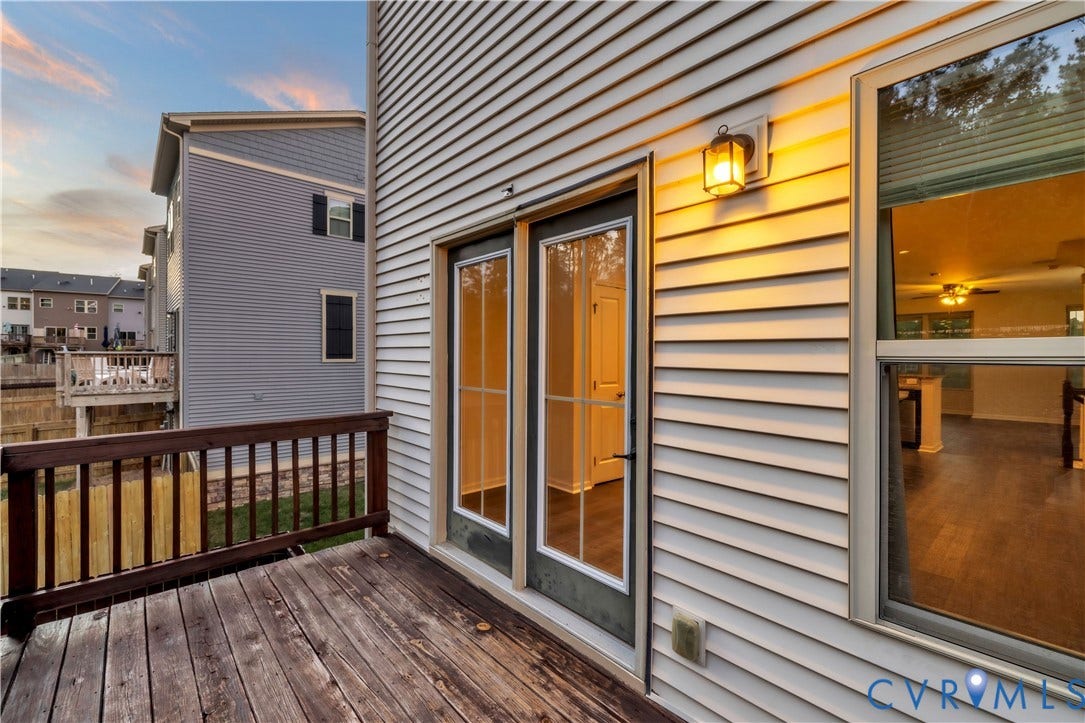 4511 Wistar Woods Trail, Richmond, VA 23228 Exterior deck featuring wood-plank flooring, a wood railing, dual glass-panel doors, and wall-mounted exterior lighting