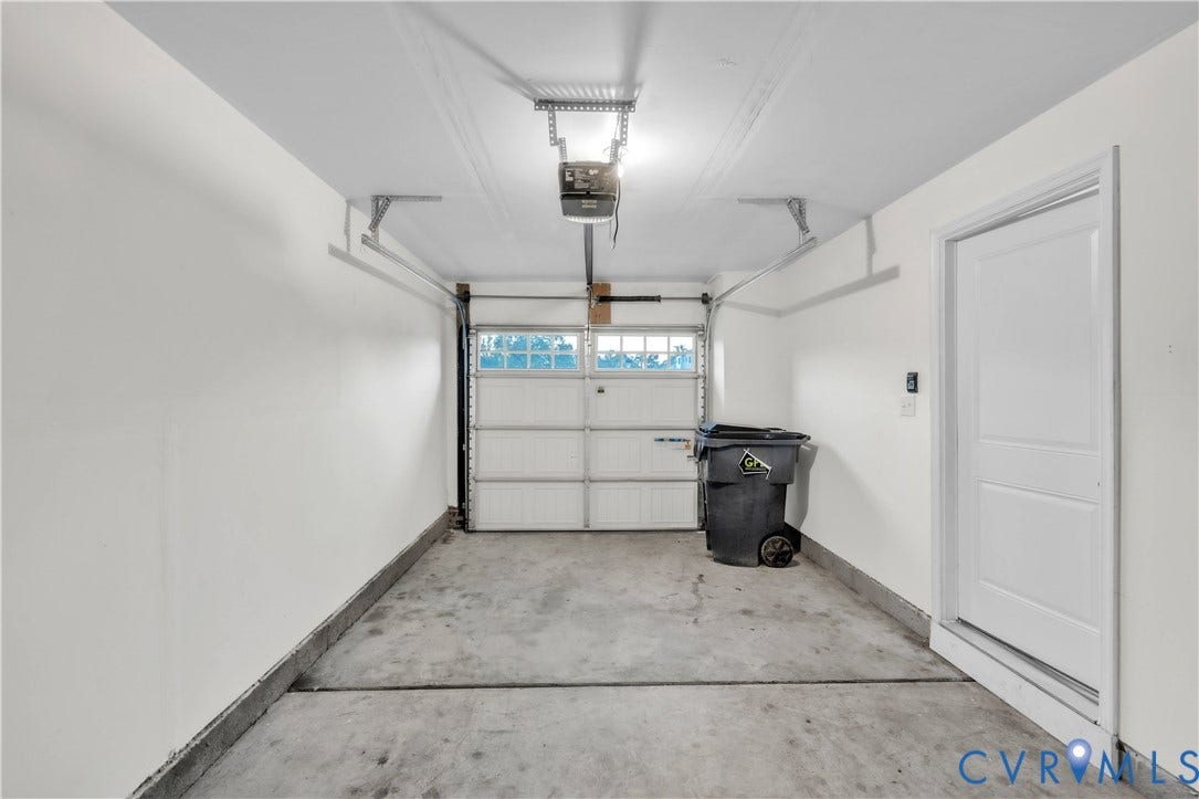 4511 Wistar Woods Trail, Richmond, VA 23228 Enclosed garage space featuring a paneled sectional door with integrated window inserts, concrete flooring, and a dedicated side-entry door