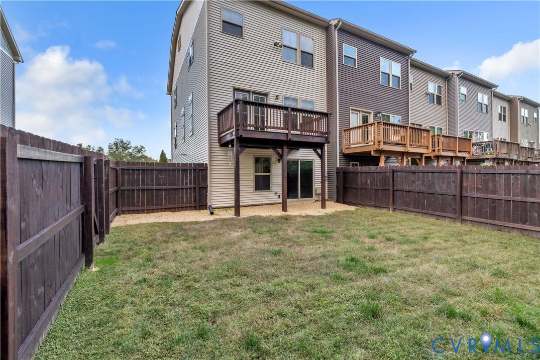 4511 Wistar Woods Trail, Richmond, VA 23228 Rear exterior featuring a wood-plank deck, sliding glass door, and a private, fully fenced backyard