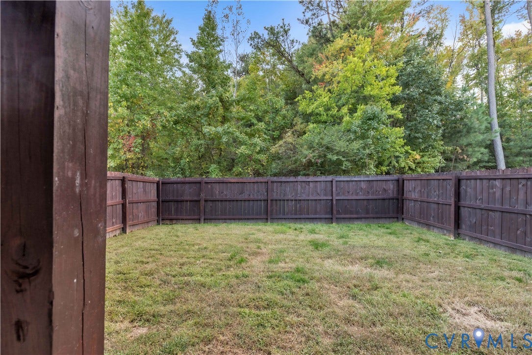 4511 Wistar Woods Trail, Richmond, VA 23228 Backyard featuring a wood-panel privacy fence and a natural grass lawn, bordered by mature trees