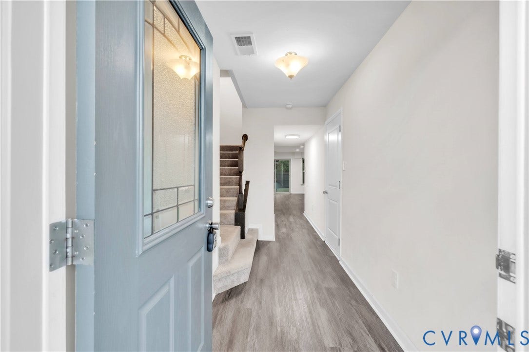 4511 Wistar Woods Trail, Richmond, VA 23228 Entryway featuring a light blue front door with a textured glass panel, wood-finish flooring, and a staircase with dark wood-toned handrails