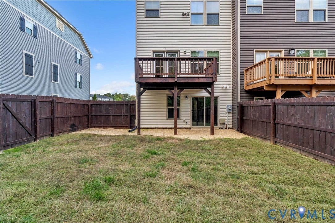 4511 Wistar Woods Trail, Richmond, VA 23228 Rear exterior featuring a raised wood deck, ground-level stone patio, and perimeter wood privacy fencing