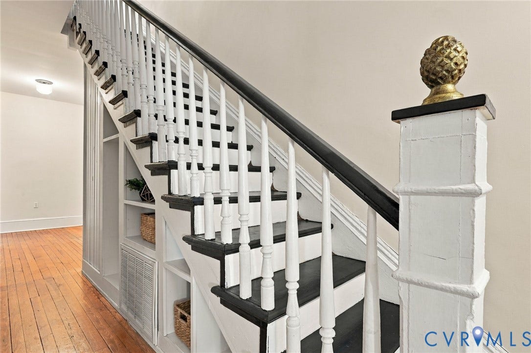 522 N 27th Street, Church Hill, Richmond, VA 23223 Staircase featuring white balusters, contrasting dark treads, a handrail, an ornate newel post cap, and built-in under-stair shelving