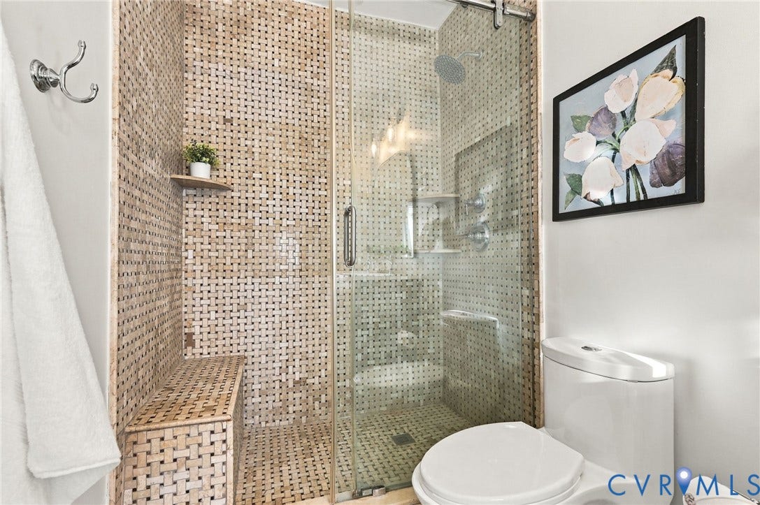 522 N 27th Street, Church Hill, Richmond, VA 23223 Walk-in shower featuring a built-in tiled bench, textured stone-style wall tile, glass enclosure with a sliding door, and an overhead rainfall showerhead