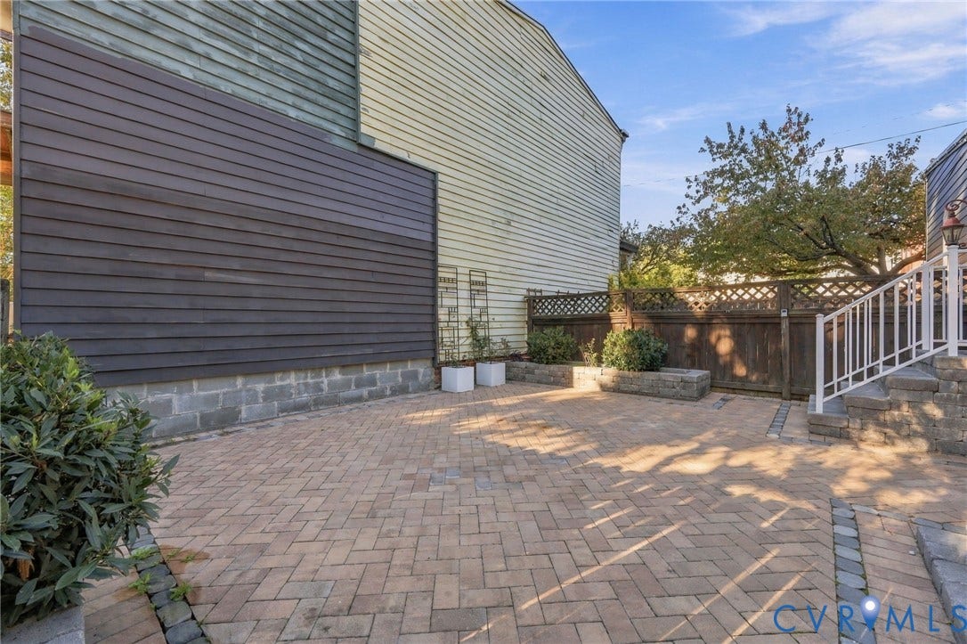 522 N 27th Street, Church Hill, Richmond, VA 23223 Herringbone-patterned paver patio featuring built-in stone planters, wood lattice-top fencing, and a white metal staircase