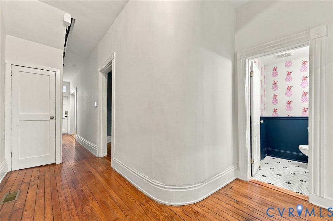 522 N 27th Street, Church Hill, Richmond, VA 23223 Hallway featuring wood-finish flooring, a curved architectural wall, and classic multi-panel interior doors with traditional millwork trim and view of the curved corner wall.