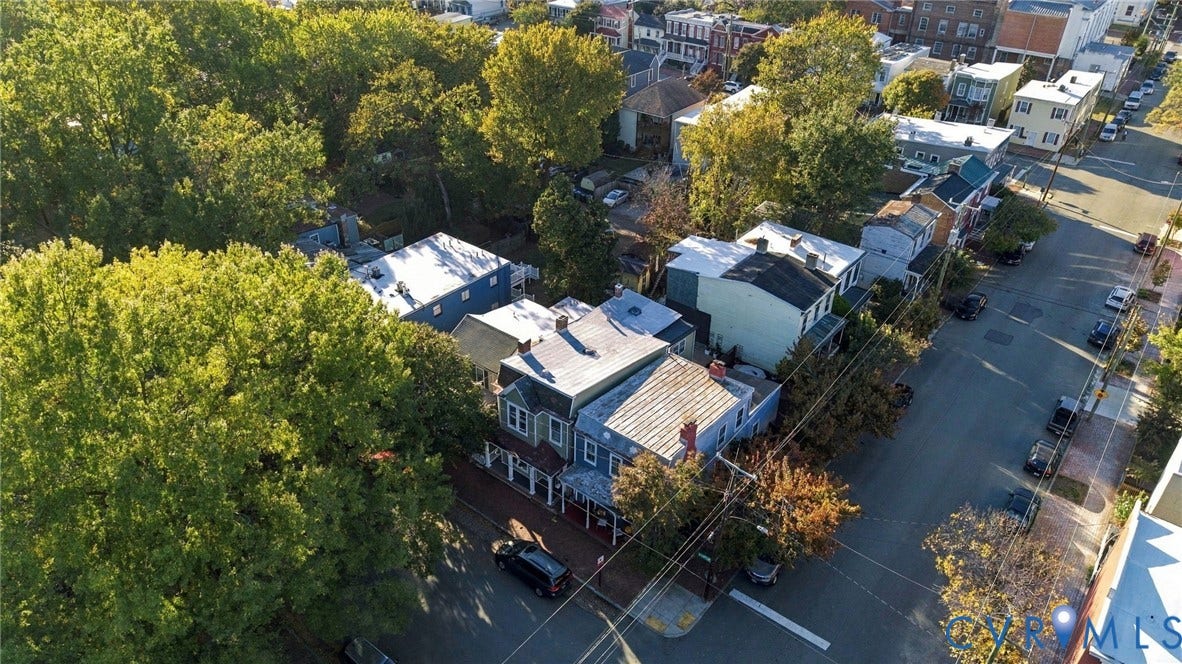 522 N 27th Street, Church Hill, Richmond, VA 23223 Aerial view of multi-story residence featuring a covered front porch, metal roof, and brick exterior detailing, situated on a corner lot with established trees