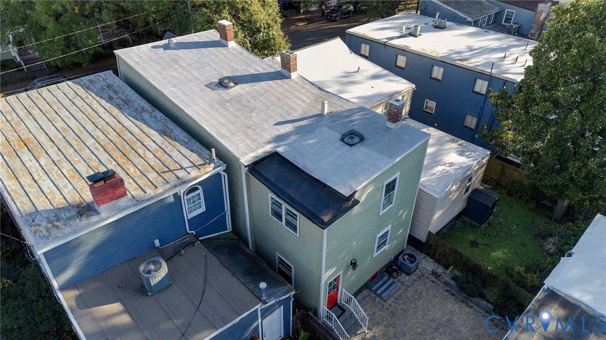 522 N 27th Street, Church Hill, Richmond, VA 23223 Multi-level exterior featuring light green siding, two rooftop skylights, three brick chimneys, and an outdoor staircase