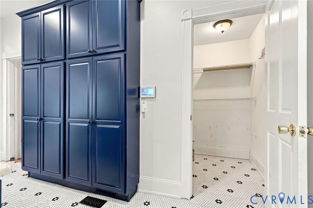522 N 27th Street, Church Hill, Richmond, VA 23223 Floor-to-ceiling cabinetry with navy blue shaker-style doors, black circular hardware, geometric tile flooring, and integrated wall-mounted smart home control panel
