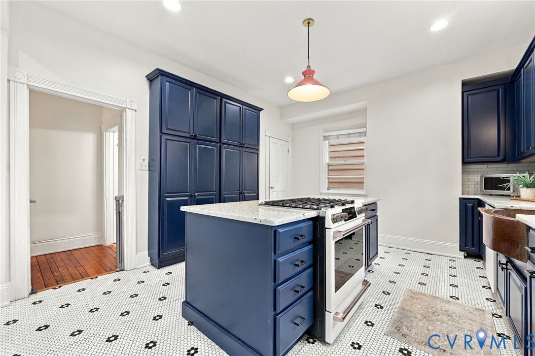 522 N 27th Street, Church Hill, Richmond, VA 23223 Kitchen featuring floor-to-ceiling blue cabinetry, a central island with a gas range and stone countertop, a copper apron-front sink, and patterned tile flooring