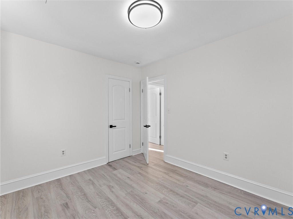 135 Elm Street, Petersburg, VA 23803 Wood-finish flooring, two-panel interior doors, matte black lever hardware, and a modern circular flush-mount ceiling light fixture