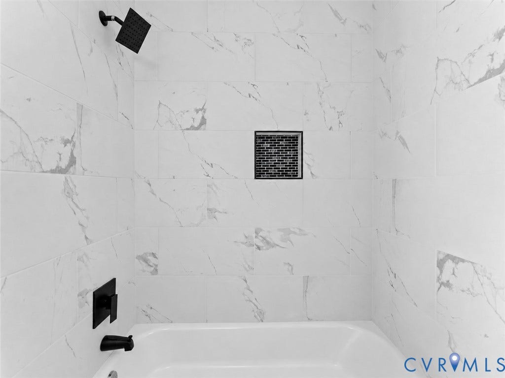 135 Elm Street, Petersburg, VA 23803 Shower enclosure featuring large-format tile with veining, matte black rainfall showerhead, matching wall-mounted faucet and tub spout, and a built-in recessed tile niche