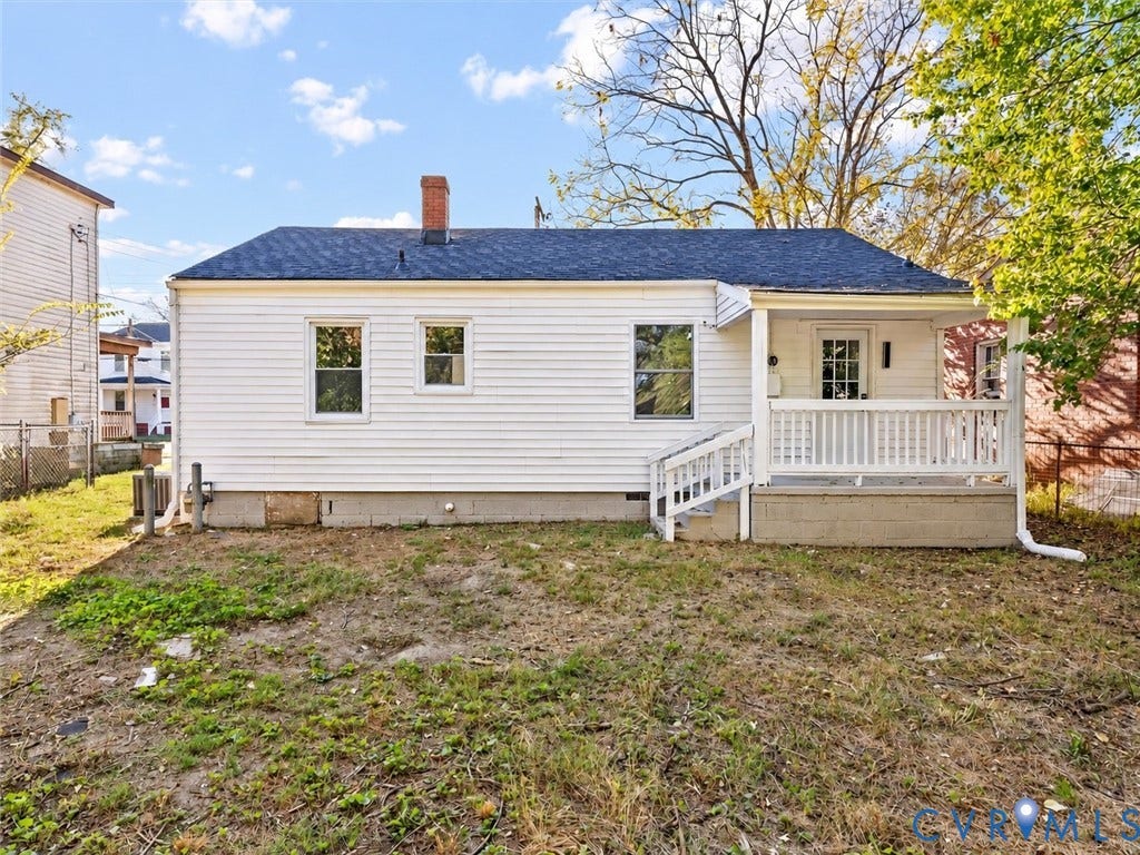 135 Elm Street, Petersburg, VA 23803 Single-story exterior featuring white vinyl siding, a gabled roof with asphalt shingles, a brick chimney, and a covered front porch with a white railing