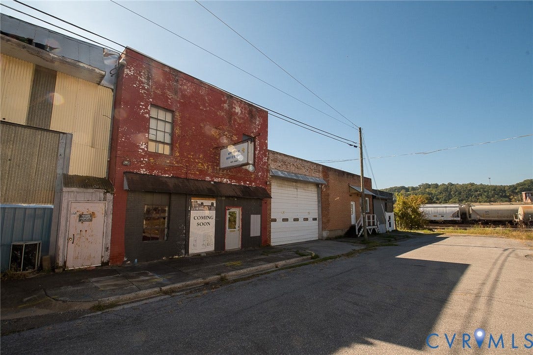 109 E Oak Street, Covington, VA 24426 Multi-story red brick masonry facade featuring large metal roll-up warehouse door, storefront entrance, and corrugated metal siding accents
