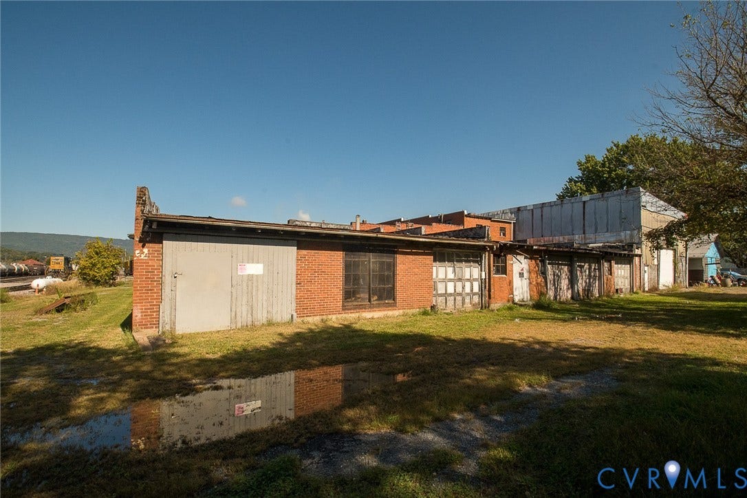 109 E Oak Street, Covington, VA 24426 Multi-bay brick structure featuring multiple metal roll-up doors, industrial-style window groupings, and a low-profile flat roof design