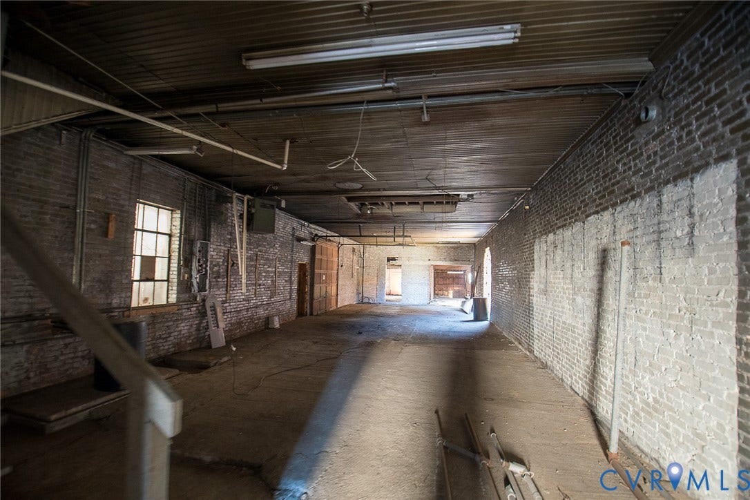 109 E Oak Street, Covington, VA 24426 Expansive interior space featuring exposed brick masonry walls, wood-plank ceiling, industrial-style multi-pane windows, and concrete flooring