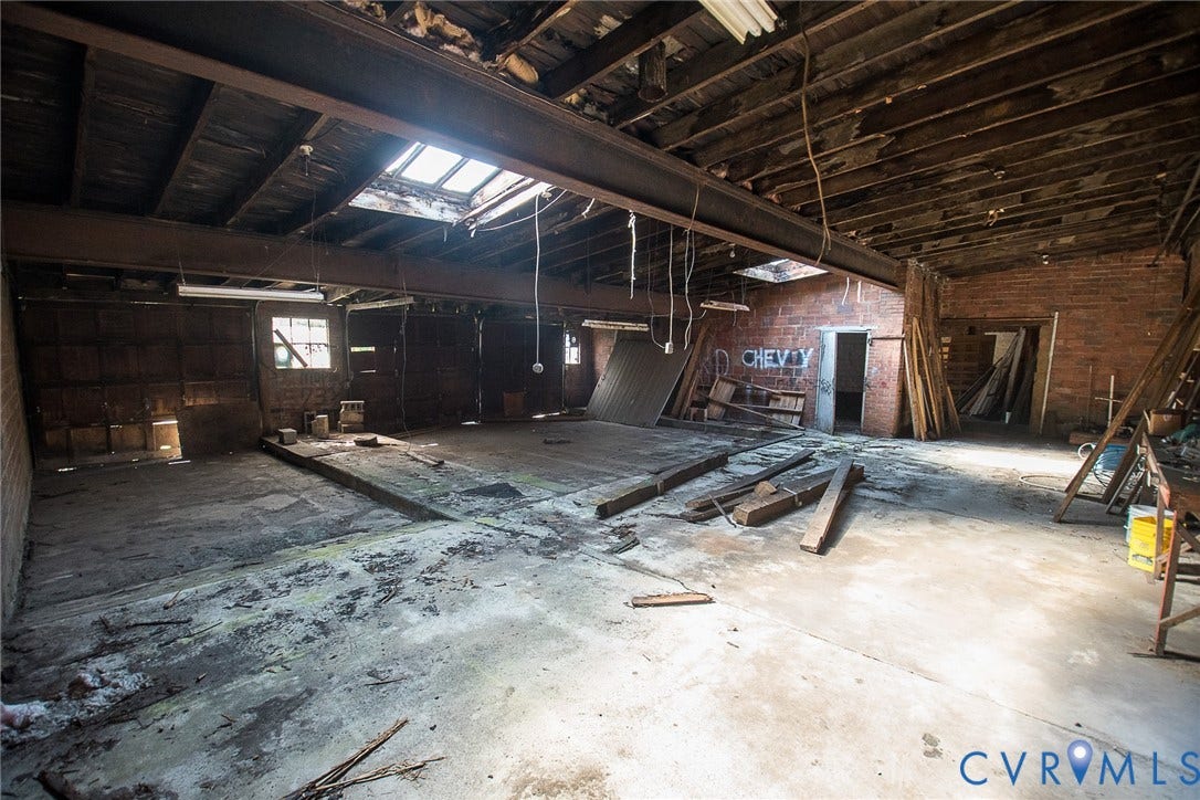 109 E Oak Street, Covington, VA 24426 Open-concept interior featuring exposed brick walls, steel support beams, concrete flooring, and multiple ceiling skylights
