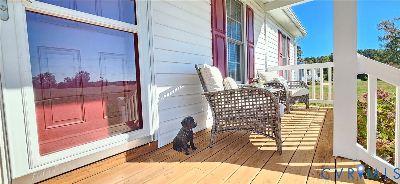 8605 Howerton Road, Center Cross, VA 22437 Covered front porch featuring natural wood decking, white vinyl siding, red window shutters, and white railings