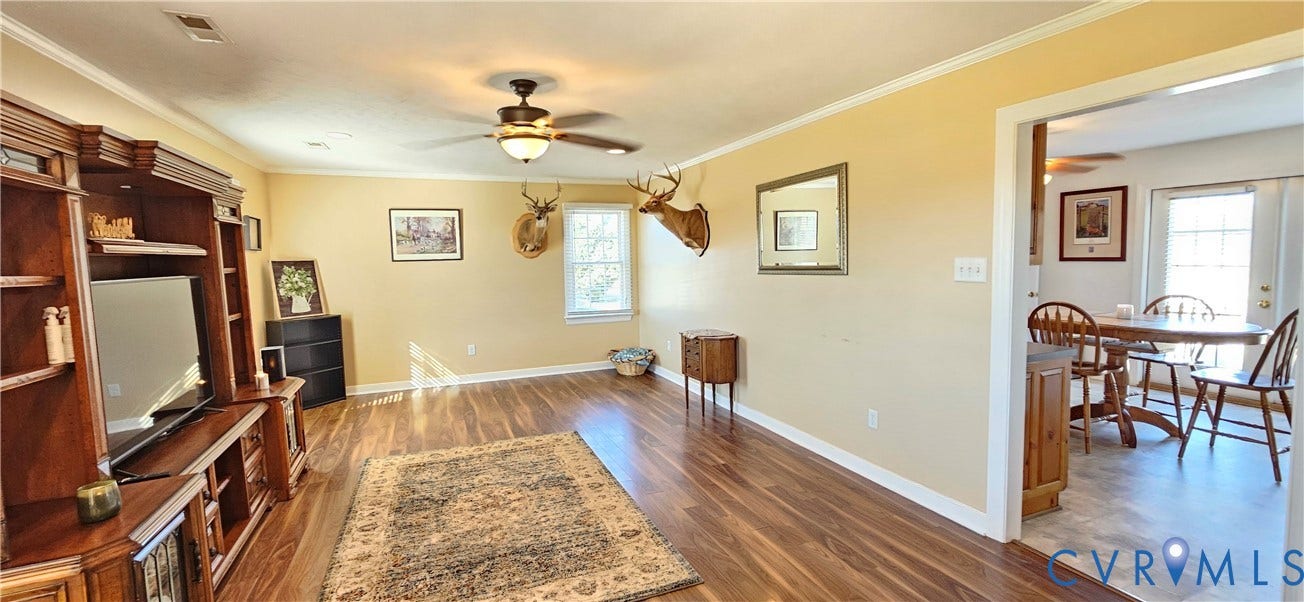 8605 Howerton Road, Center Cross, VA 22437 Living area featuring wood-finish flooring, a ceiling fan with integrated light fixture, and a built-in wooden media center